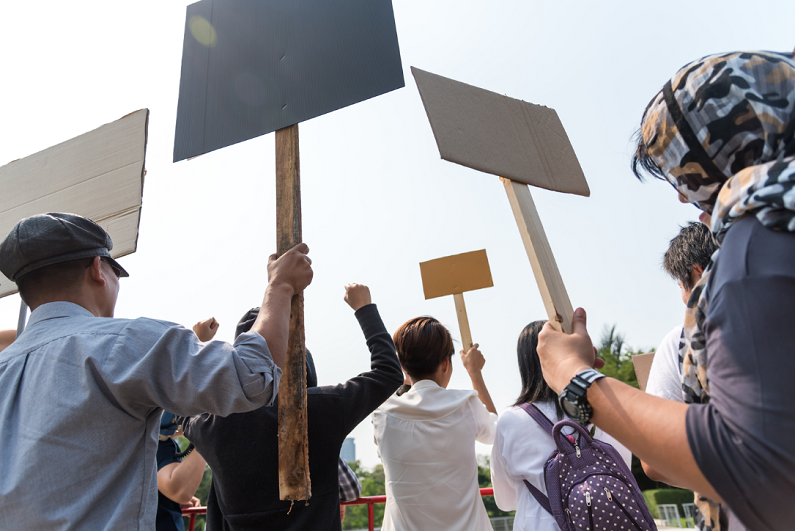 Men and women share a protest sign hold a megaphone.