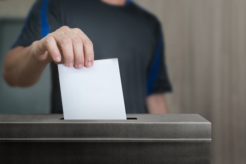 male inserting vote in ballot box