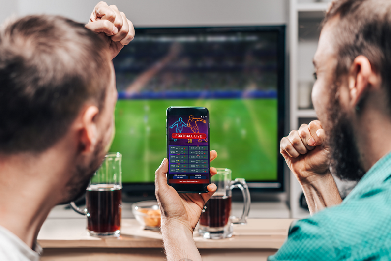 Two males watching soccer game and celebrating winning bet