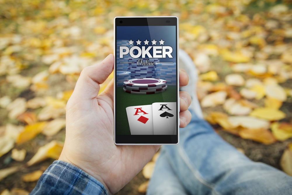 man holding smartphone with mobile poker app outdoors