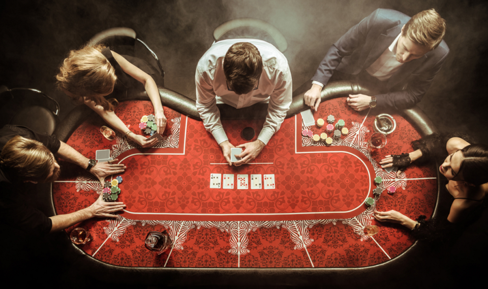 top view of men and women playing poker in casino