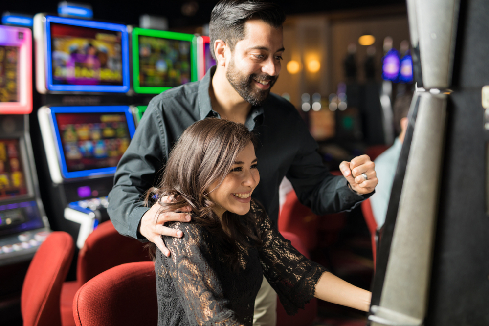 smiling man and woman playing at slot machine