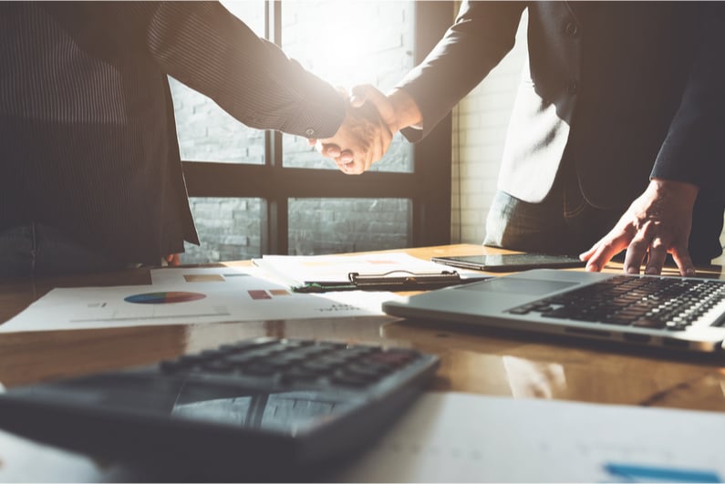 Two businesspeople shake hands over a conference table