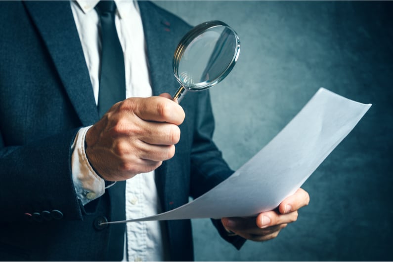 Man examining a piece of paper with a magnifying glass