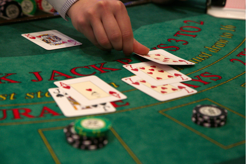 Blackjack dealer laying a third red 7 for a player