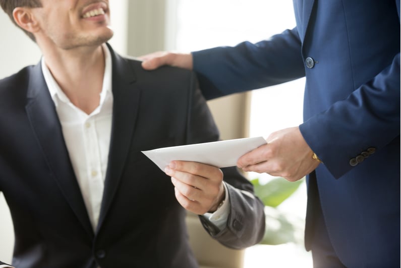 Boss handing employee a cash bonus in an envelope