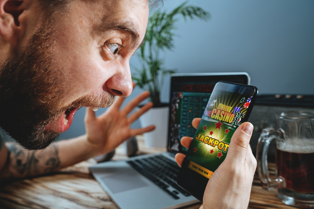 man puts on an excited face as he wins a mobile casino game