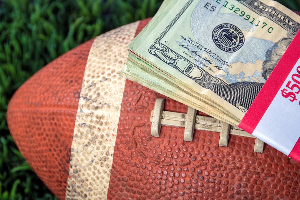 American football with wad of cash