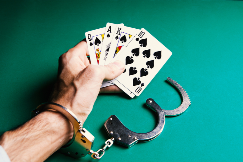 Handcuffed hand holding playing cards